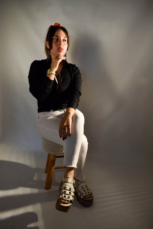 Portrait of a beautiful brunette girl in a black jacket and white pants