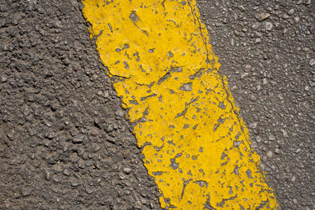 Texture of a worn yellow line on an asphalt road. Close-up. Top view.
