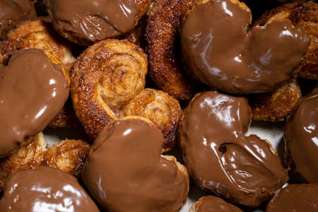 Palmier biscuits covered of chocolate. Top view close-up. Heart-shaped puff pastry, pig's ear, palm...