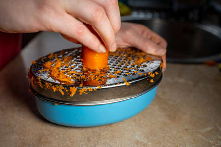 Grating a carrot with a grater. Close.up. . Homemade cook.