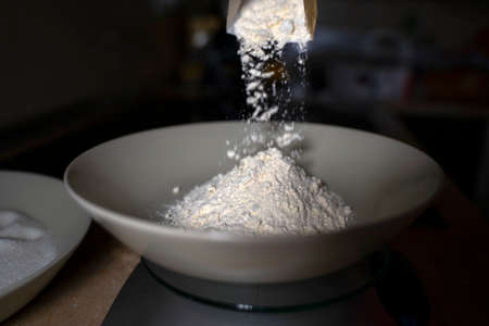 Pouring flour into a deep plate. Dark background.の写真素材