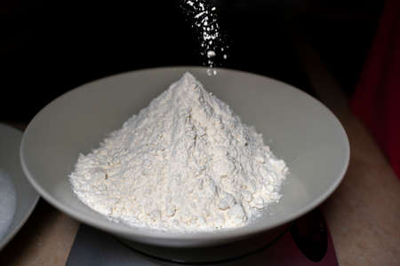 Pouring flour into a deep plate. High angle.