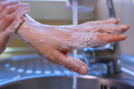 Washing hands and arms properly. Hygiene concept. Rubbing with soap and water.の写真素材