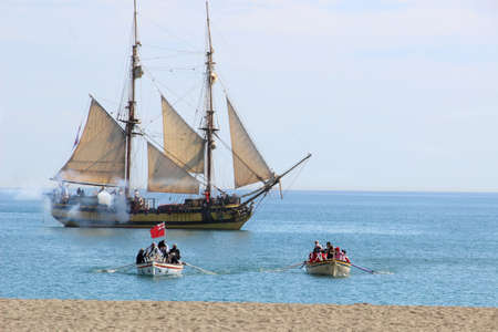 Malaga, Spain - October 26, 2014: Brig La Grace firing its cannons, soldiers row in two boats....