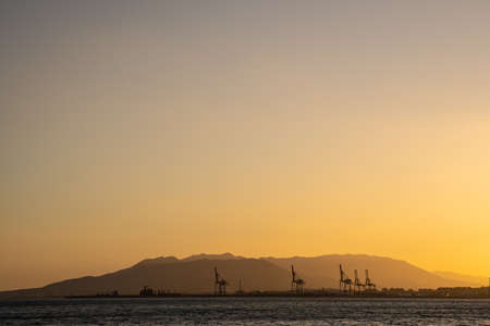Summer sunset. Orange sky over the sea, mountains on the horizon with copy space.