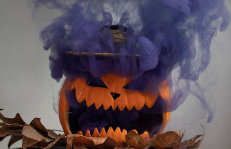 Halloween pumpkin blowing colored smokeの写真素材