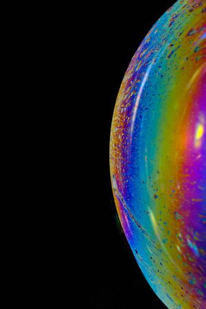 Colorful and shiny bubble background. Abstract macro photography. Close-up of colorful soap bubble on a black background.の写真素材