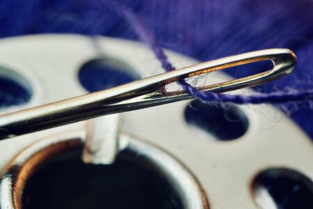 Detail of a sewing thread in the eye of a needle.