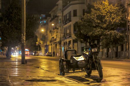 night scene, rainy street in havana cuba with parked double motorcycle
