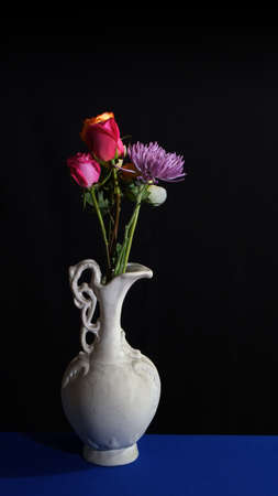 Flowers in old white ceramic vase on dark backgroundの写真素材