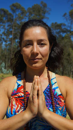 Young latin woman sitting doing yoga in the parkの写真素材
