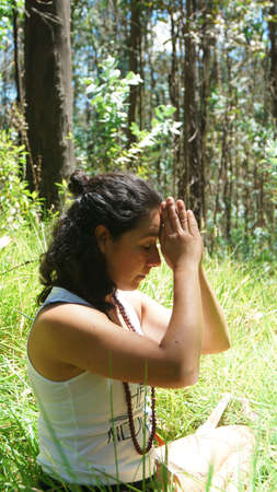 Young latin woman doing yoga in the woodsの写真素材