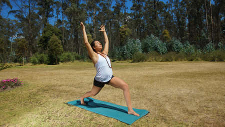 Young latin woman doing yoga in the park on yoga matの写真素材
