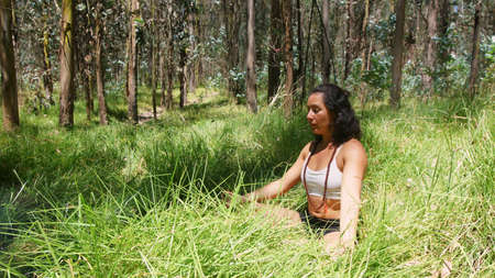 Young latin woman doing yoga in the woodsの写真素材