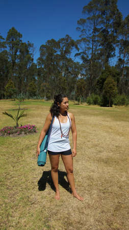 Young latin woman with yoga mat in the middle of the parkの写真素材