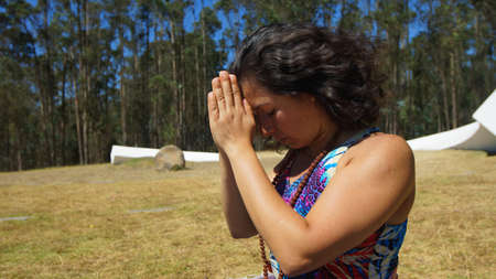 Young latin woman sitting doing yoga in the parkの写真素材
