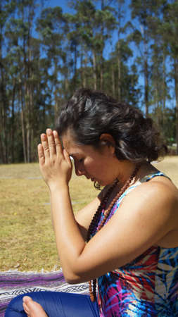 Young latin woman sitting doing yoga in the parkの写真素材