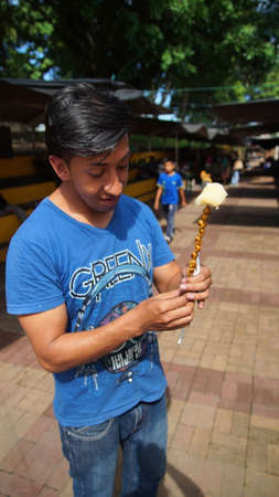 Puerto Francisco de Orellana, Orellana / Ecuador - June 7 2016: Ecuadorian tourist eating Chontacuros or Mayones (roasted worms) in a popular market in the town of Cocaのeditorial素材
