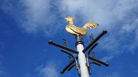 Bronze vane with rooster shape on blue sky background with cloudsの写真素材