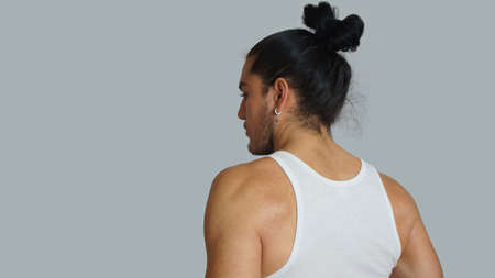 Young hispanic male with gathered hair done in white sleeveless t-shirt, seen from behind