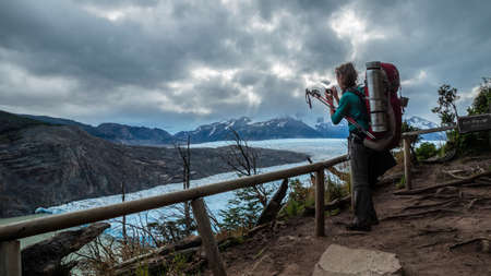 Torres del Paine, Magallanes / Chile, June 8 2016: Scout woman with her backpack taking photograph of the Gray Glacier in Torres del Paine National Park in Chilean Patagoniaのeditorial素材