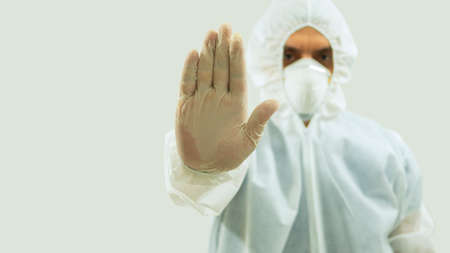 Front view of doctor with mask and bioprotective suit with arm extended forward and his right hand...