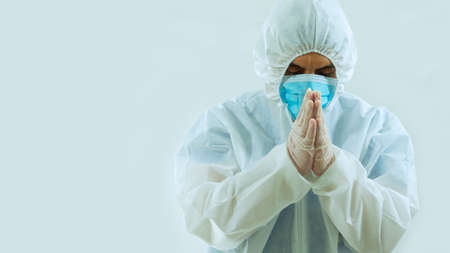Front view of doctor with blue mask and bioprotective suit with head tilted down and eyes closed...