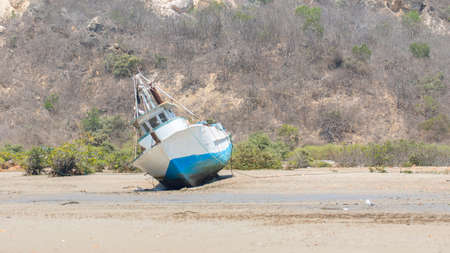 Fishing blue boat stranded on the estuary waiting for the tide to rise