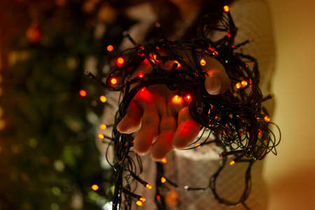 Close-up of woman's hands with red, green and blue colored lights to decorate the Christmas tree