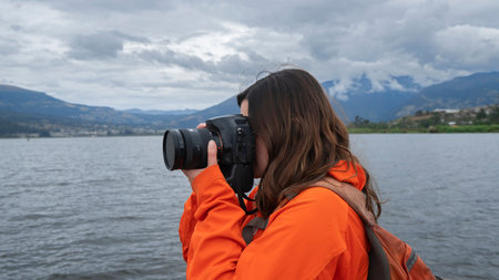 Close up view of beautiful young Latin American woman dressed in orange jacket with backpack seen...