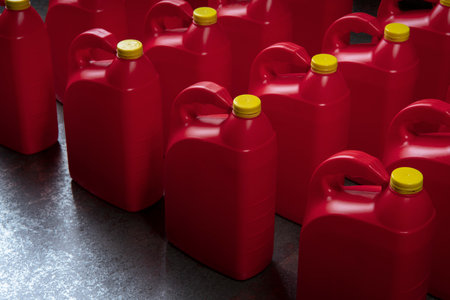 Top view of arranged red plastic motor oil bottles, containers with handle and yellow screw cap on...
