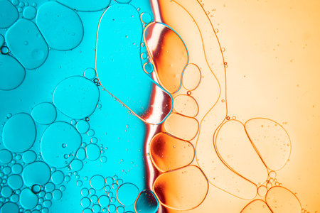 Abstract composition with water and oil drops against a two-tone blue and orange backgroundの写真素材