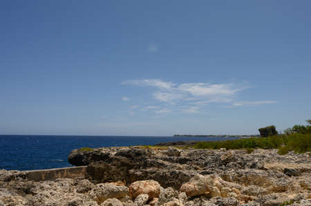 Photo of a sandy beach in the foreground from the Dominican Republic. The picture clearly shows the magnificent sand from the Atlantic Ocean and the bright blue sky, forming a horizon line.の写真素材