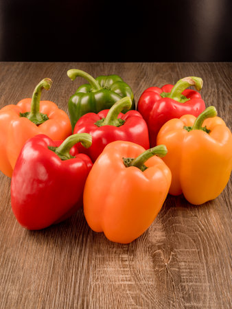 Photo shows peppers in three colors: yellow, red and green. Photo was taken in studio using special lighting. View of peppers is made from side.の写真素材