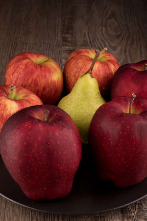 Photo shows several apples and one pear. Photo was taken in studio using special light. Red apple glistens like glossy - this is natural effect.の写真素材