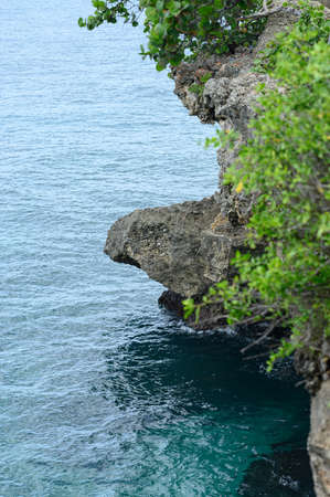 The photo shows a sheer cliff in the Caribbean Sea. The ocean water is clear and blue. Perfectly...