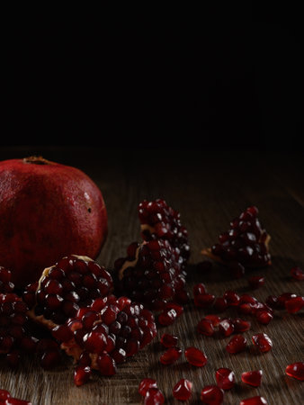 A close-up photo of a pomegranate fruit with great focus. The picture of pomegranate fruit seeds is made in semi-gloomy colors. Juicy pomegranate is perfect for a snack or breakfast.の写真素材