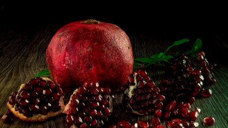 A close-up photo of a pomegranate fruit with great focus. The picture of pomegranate fruit seeds is made in semi-gloomy colors. Juicy pomegranate is perfect for a snack or breakfast.の写真素材
