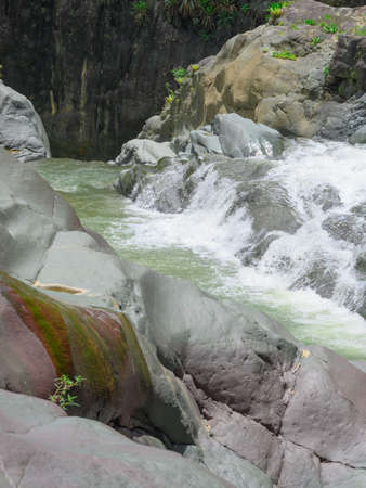 Photo shows rocky gorge in which mountain river flows. River flows through huge blocks of stones. Enchanting wildlife of Caribbean island amazes with its authenticity. Top view of mountain river.の写真素材