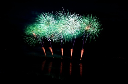 Many fireworks explosions over the lake with reflections and smoke