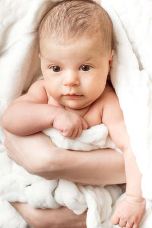 baby in his mother's warm hands looking at the cameraの写真素材