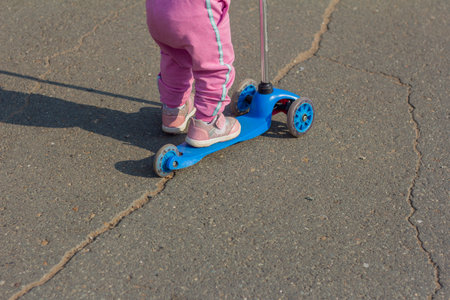 A small child learns to ride a scooter in the Parkの写真素材
