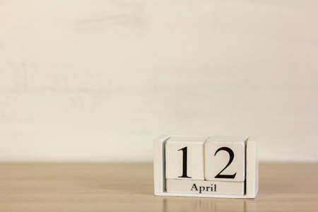 A wooden calendar with the date April 12 on the desktop.