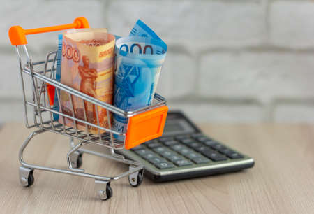 Russian money, bills of thousands, rolled up in a tube, lie in a shopping cart.