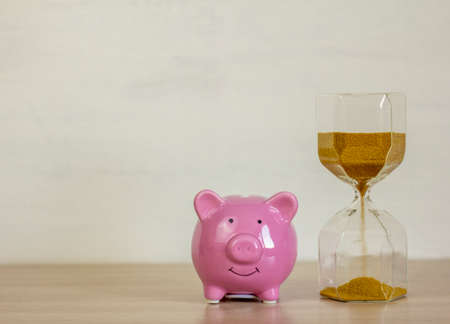 Pink piggy bank and hourglass on the table.Time is money.の写真素材