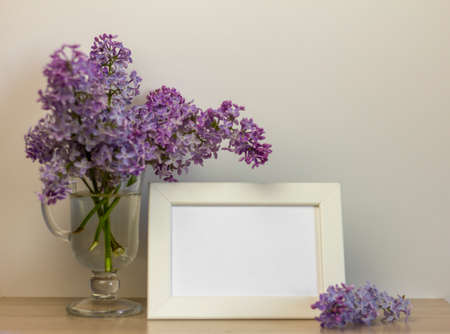 An empty photo frame and a bouquet of lilacs on a table or shelf with a copy of the spaceの写真素材