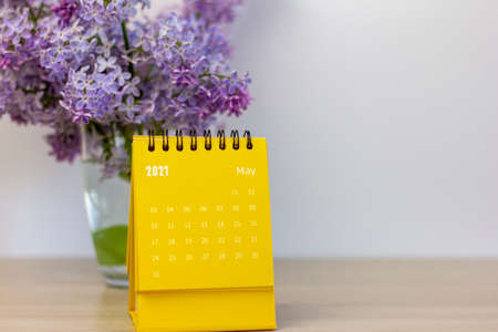 A flip calendar for May 2021 and a bouquet of lilacs on the table. Desktop calendar for planning, assigning, organizing, and managing each dateの写真素材