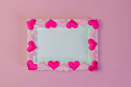 Empty photo frame decorated with hearts on a pink background, top viewの写真素材