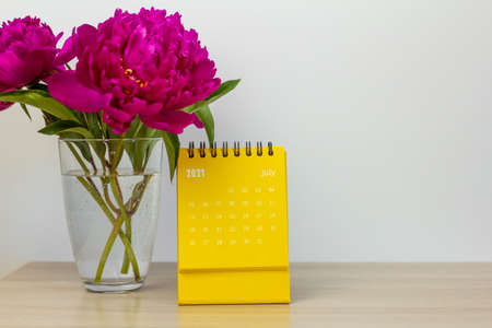 Calendar for July 2021 and peonies on the table. Desktop calendar for planning, scheduling, assigning, organizing, and managing each dateの写真素材