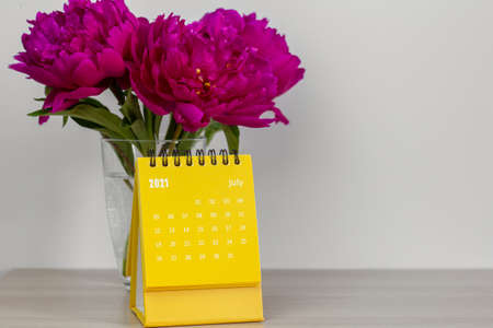 Calendar for July 2021 and peonies on the table. Desktop calendar for planning, scheduling, assigning, organizing, and managing each date.の写真素材